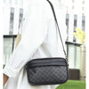 A man wearing a white shirt carries a black PU leather shoulder clutch bag.