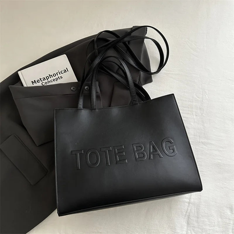 A black tote bag is shown next to a white card labeled Metaphorical Concepts on a white surface.
