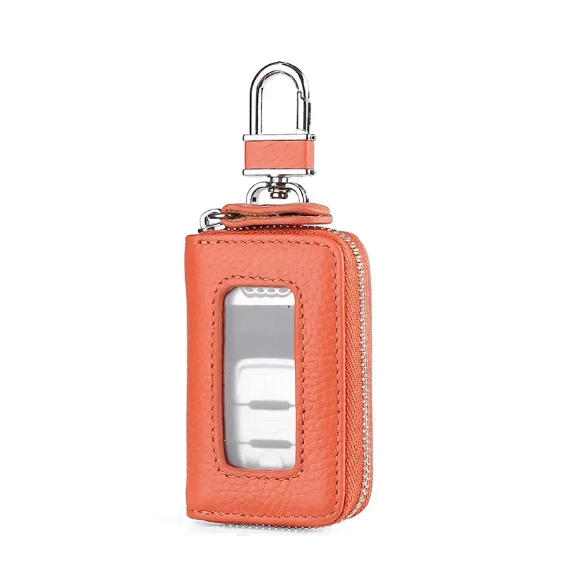 A small orange leather car key case with a transparent window and silver clasp.