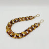 A gold-toned chain bracelet made of amber and brown acrylic links.