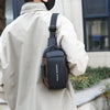 A person wearing a beige coat is holding a black durable oxford sling bag for commuting.