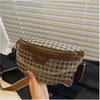 A brown leather leopard print crossbody shoulder bag resting on a dark surface near a window.
