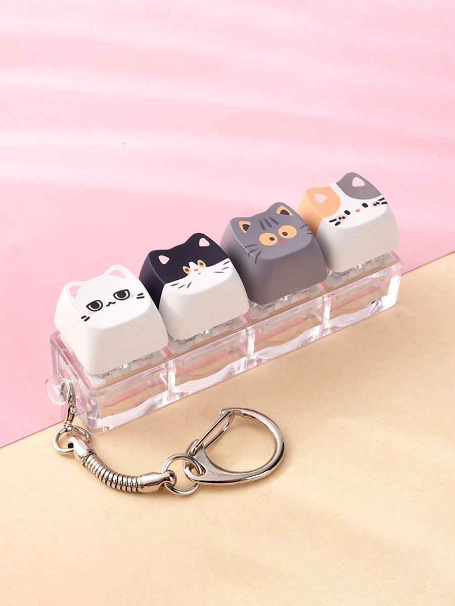 A set of five cute cat-shaped keycaps or fidget toys in various pastel colors displayed on a clear plastic tray.