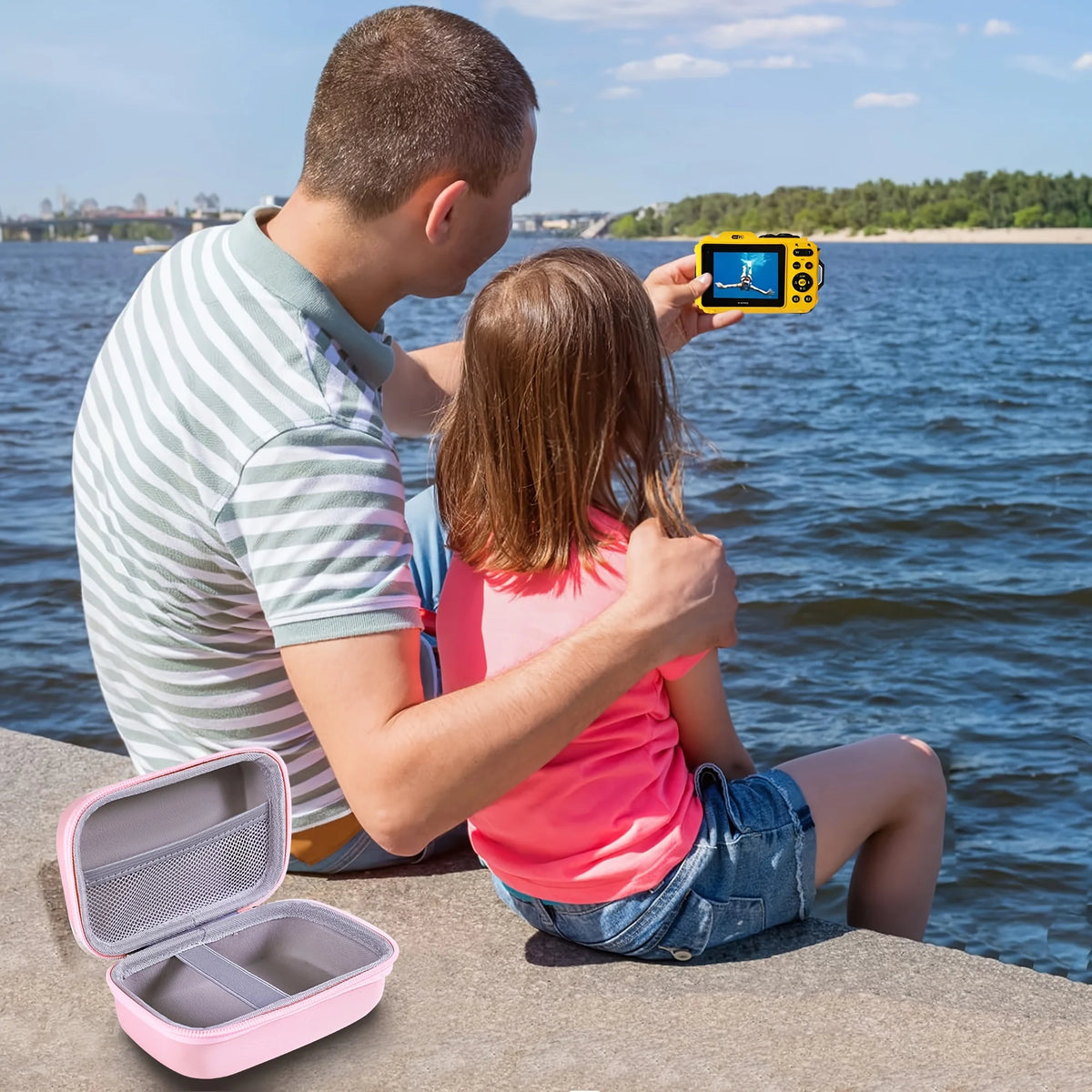 Ein Vater zeigt seiner Tochter eine gelbe Kamera, während sie in der Nähe des Wassers sind, mit einer rosa Aufbewahrungstasch