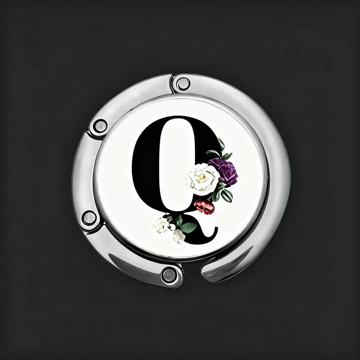 A silver, round letter Q with a floral design is shown against a dark background.
