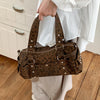 A brown leopard print shoulder bag with silver rivets being held by a person against a white background.