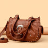 Braune Vintage Soft PU Lederhandtasche mit silberner Hardware auf beigem Untergrund.