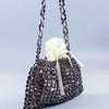 A handmade dumpling bag made of silver and gold beads tied with a white ribbon.