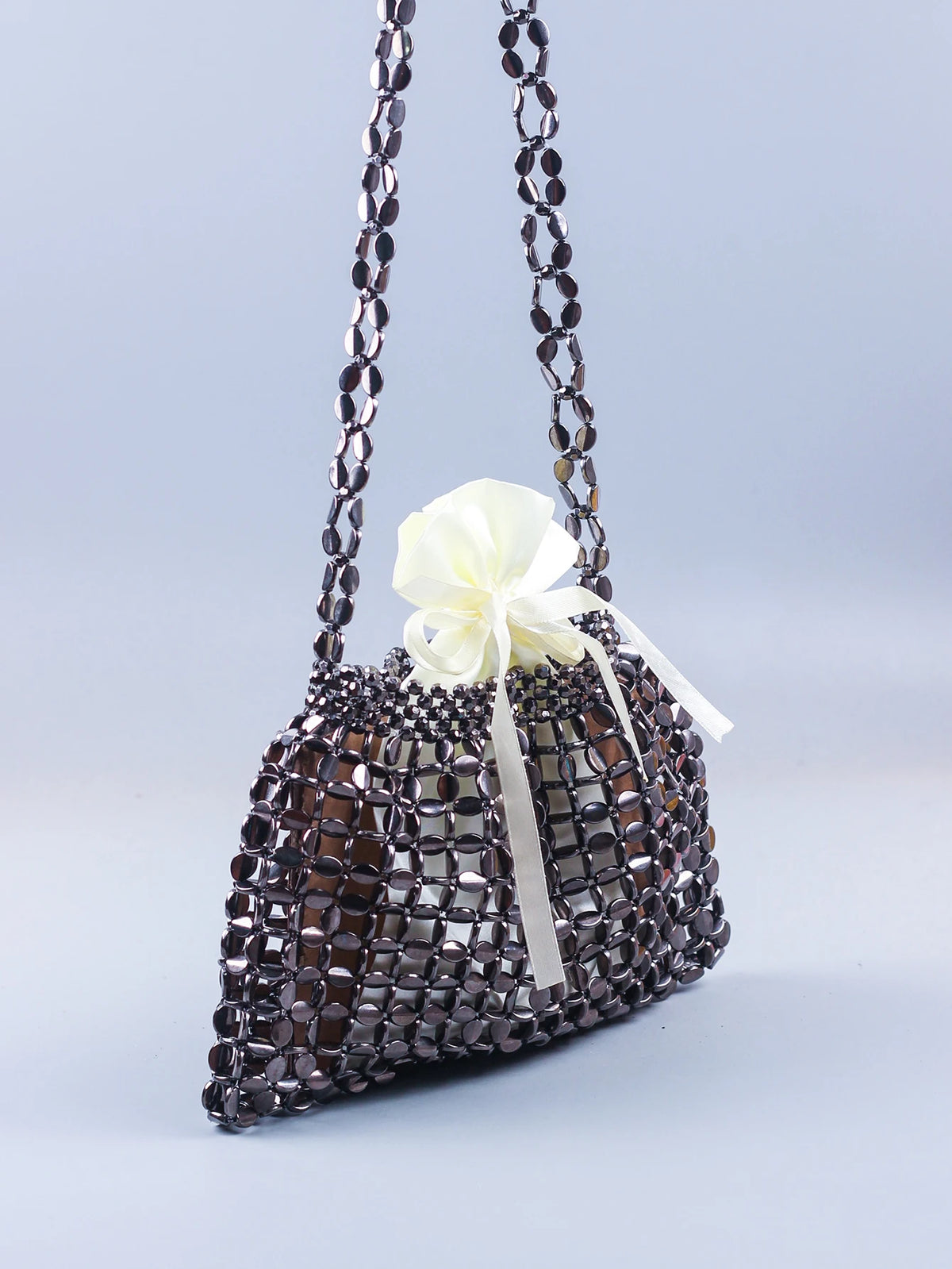 A handmade dumpling bag made of silver and gold beads tied with a white ribbon.