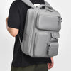 A person is wearing a gray cement ash large capacity travel backpack.