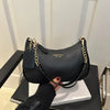 A black leather shoulder bag with gold chain detailing and a square flap is displayed on a dark surface.