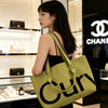 A woman holds a lime green knitted large tote bag with a black chain strap in a retail setting.