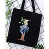 Black canvas tote bag featuring a large gold letter I with a blue floral print against a white background.