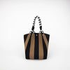 A black and tan striped knitted tote bag with a braided leather strap and silver hardware.