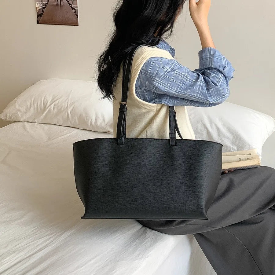 Une femme tient un sac à main noir en similicuir PU décontracté dans un cadre intérieur relaxant.