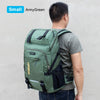 A person is shown wearing a small ArmyGreen backpack with a rain cover on a light gray background.