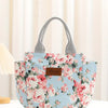 Bolsa térmica estampada floral azul claro con asas grises sobre una superficie blanca.