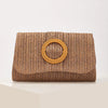 A woven straw envelope clutch in a natural brown color with a circular detail.