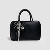 Black leather handbag with a black handle featuring a bowknot star keychain charm