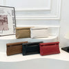 Una exhibición de cuatro elegantes bolsos de mano tejidos en tonos beige, crema, negro y rojo.