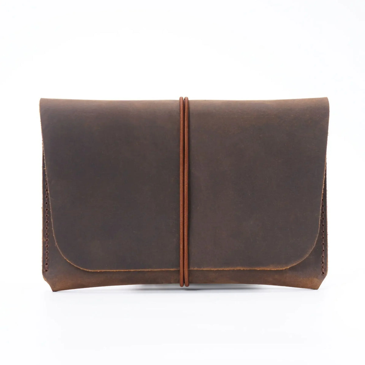 A dark brown minimalist full-grain leather passport holder and card wallet with a flap closure.