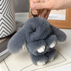 A soft gray plush rabbit fur keychain with white inner ears is shown against a light background.