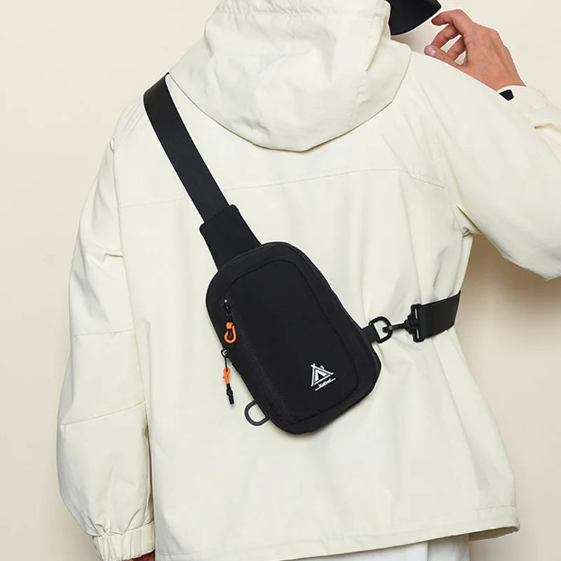 A white jacket features a black nylon sling crossbody bag with an orange detail on the front.
