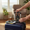 A hand is placing a black luggage tag with an 'A' privacy cover onto a dark blue PU leather suitcase.