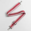 A red and white patterned leather handbag strap with silver hardware.