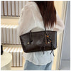 A woman holds a brown classic PU leather tote bag against a light background.