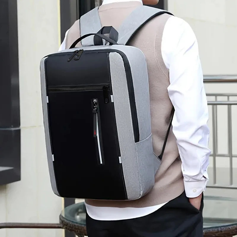 A person is carrying a gray and black durable laptop backpack over their shoulder.
