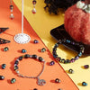 A collection of polymer clay bracelets, beads, and a display stand are arranged on an orange surface.
