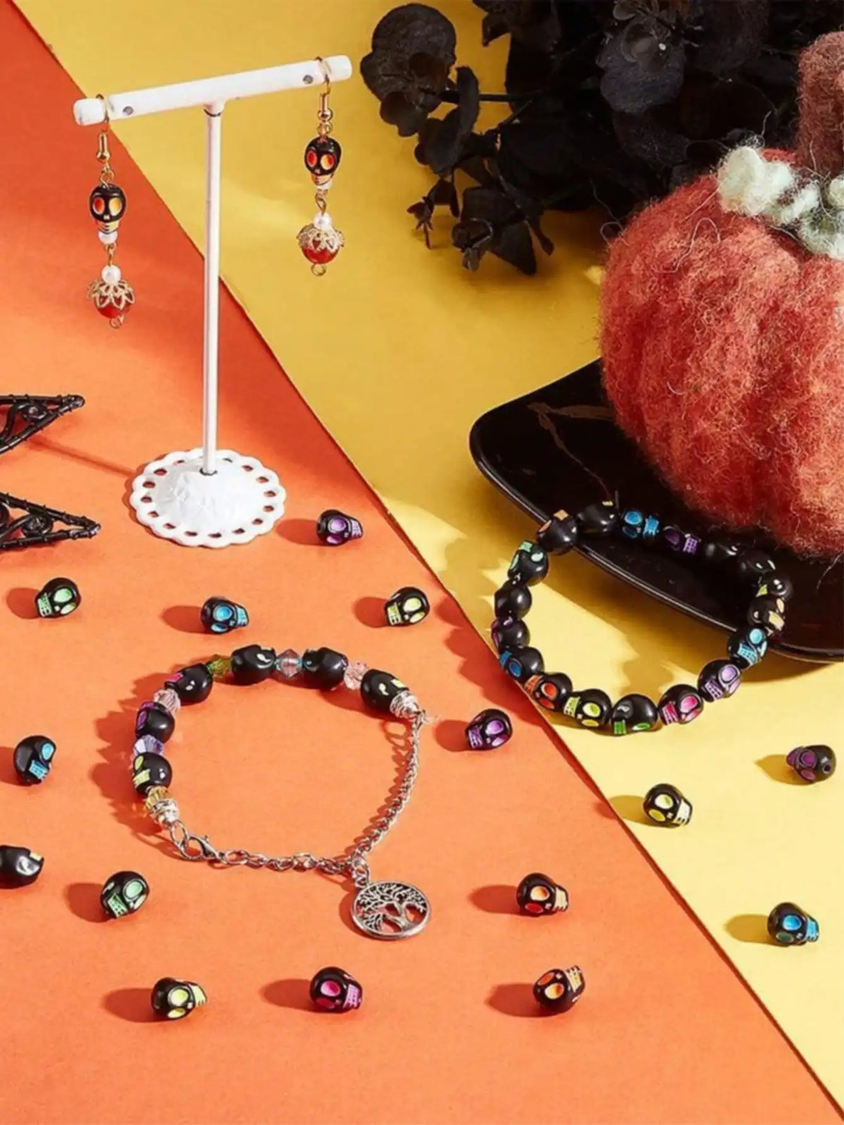 A collection of polymer clay bracelets, beads, and a display stand are arranged on an orange surface.