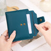 A teal RFID blocking bi-fold card holder wallet is held by a hand, showing its design and texture.