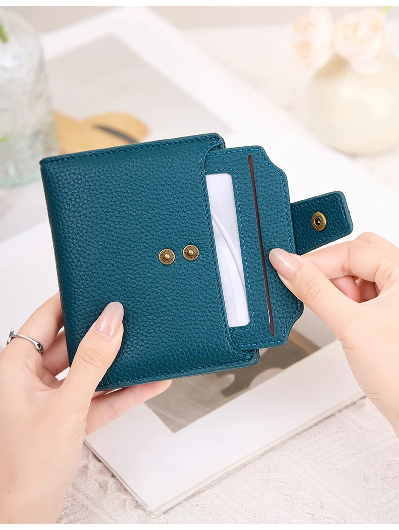 A teal RFID blocking bi-fold card holder wallet is held by a hand, showing its design and texture.