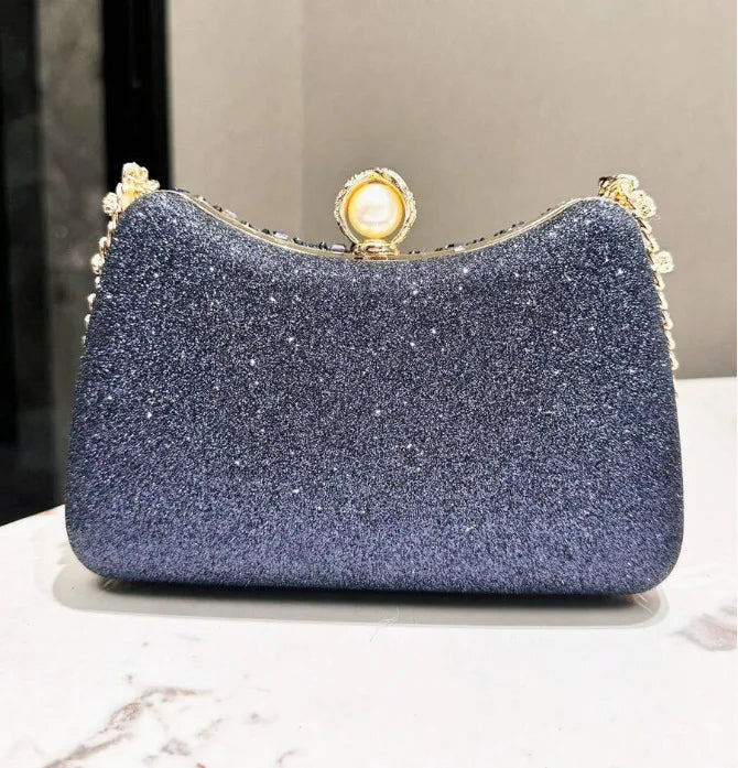 A dark blue glittery evening clutch featuring gold rhinestone embellishments and a decorative clasp.
