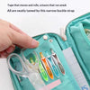 A hand is shown fastening a narrow buckle strap on a teal pencil case, securing various tools inside.