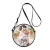 A black strap is attached to a round bag featuring two kittens, one black and one orange.