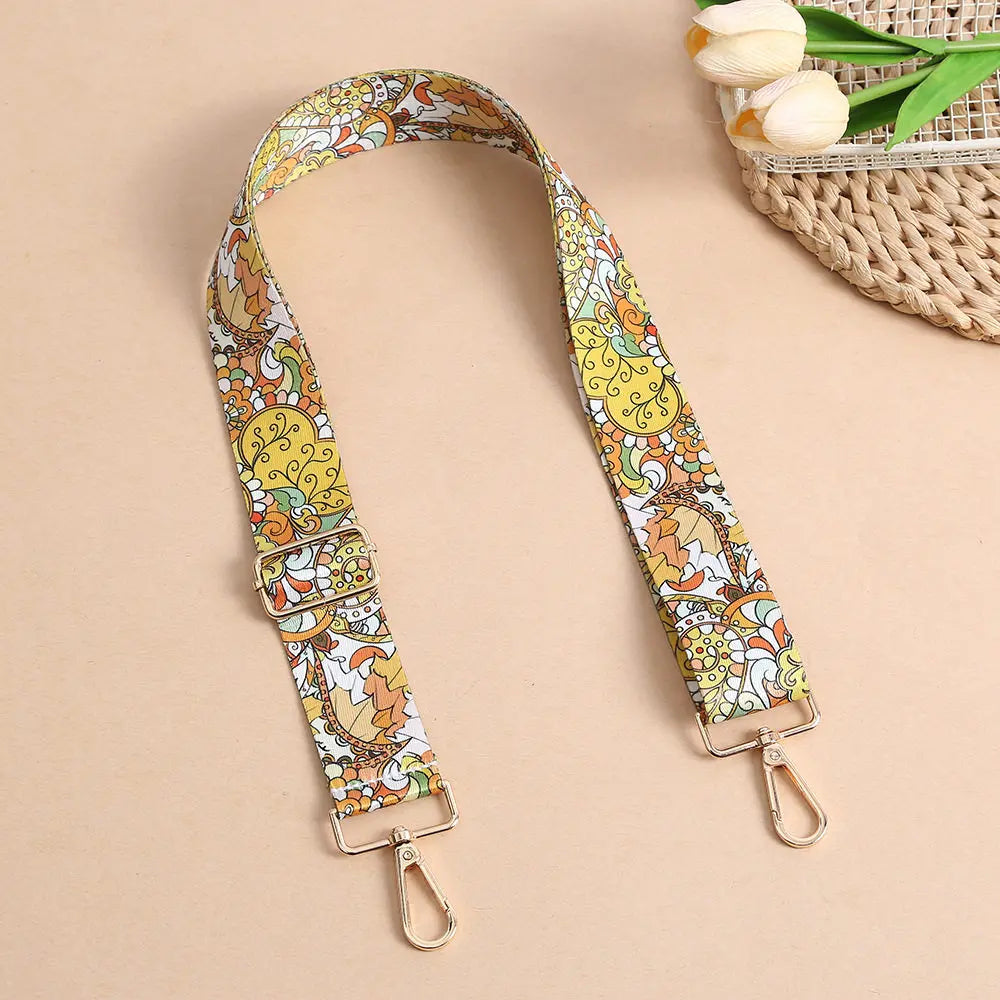 An adjustable bohemian printed crossbody strap featuring yellow, orange, and white floral patterns.