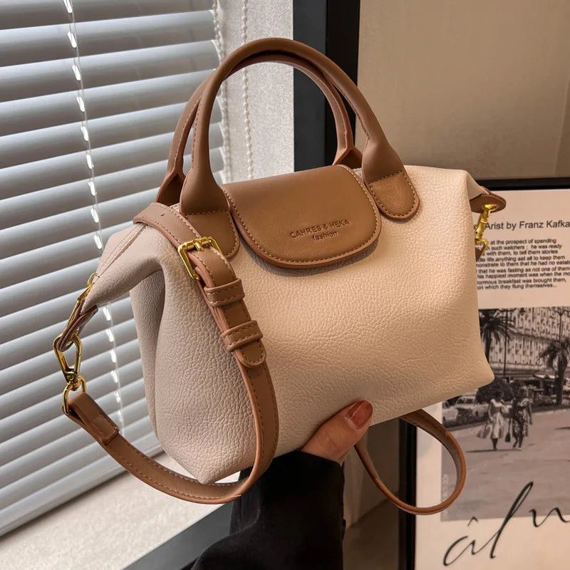 A tan vintage PU leather crossbody handbag is displayed against a white slatted blind.
