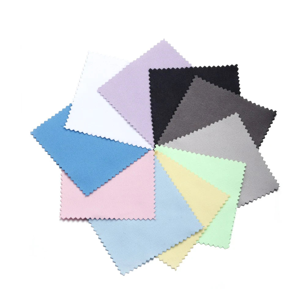 A collection of small, square polishing cloths in various pastel and dark shades of pink, blue, gray, and black.
