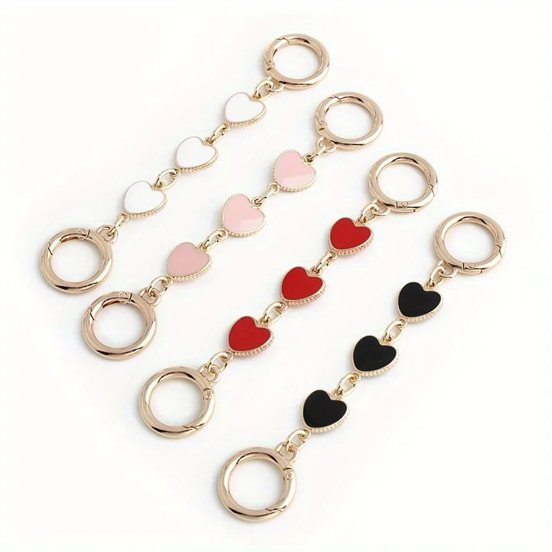 A set of gold-toned metal chain shoulder straps with heart-shaped extensions in pink and red colors.
