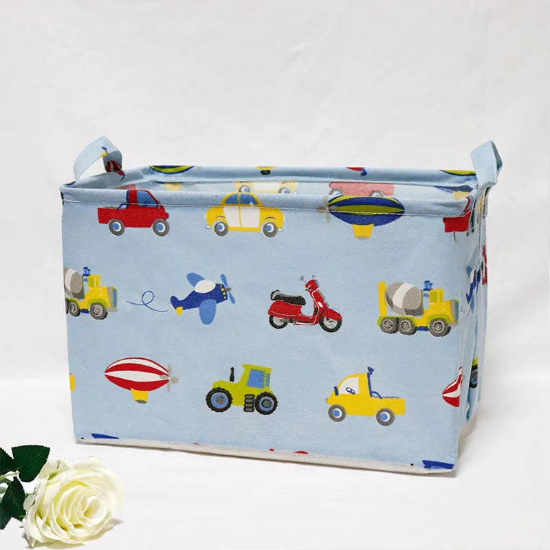 Light blue fabric storage basket with handles featuring colorful toy vehicles and animals
