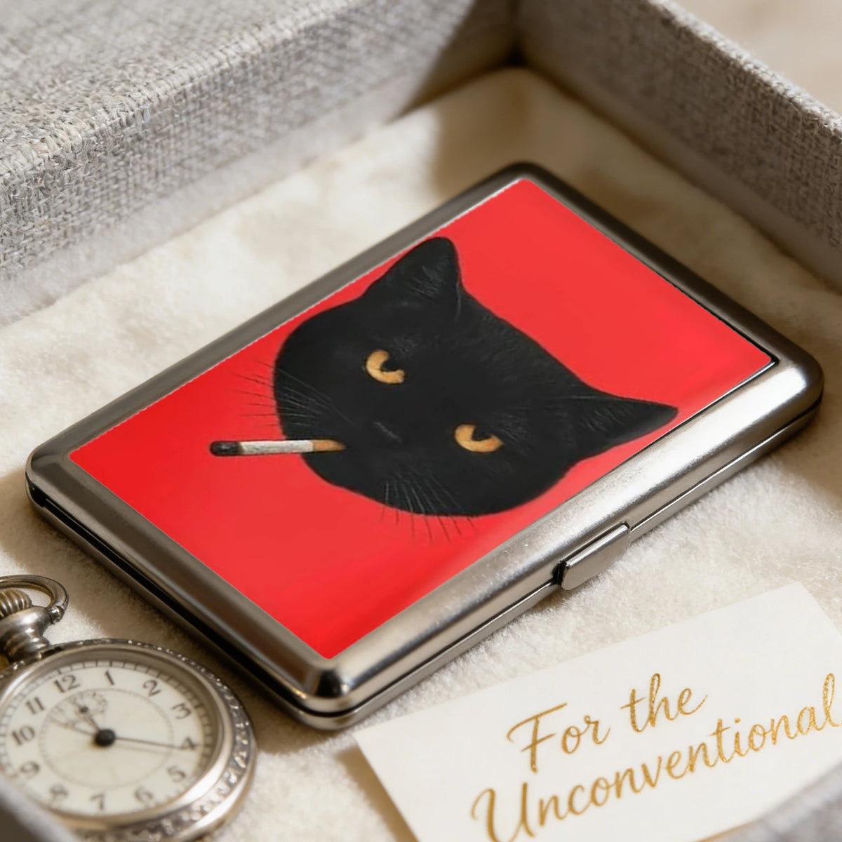 A black cat silhouette with a cigarette resting on its nose is displayed inside an Art Deco metal card holder.