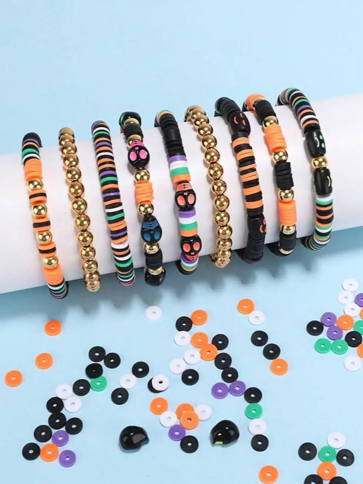A collection of colorful polymer clay bracelets in various patterns and colors laid out on a light blue background.