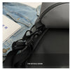 A close-up of a black travel tote bag featuring a zippered compartment and black strap details against a denim background.