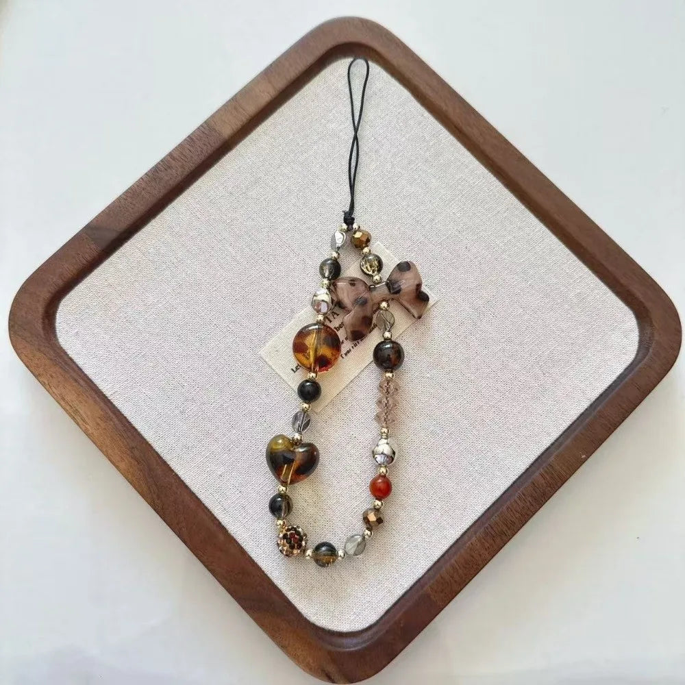 Leopard print bowknot phone lanyard featuring heart-shaped beads and a decorative bow.