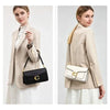 A woman models a beige blazer and white skirt, holding a premium textured shoulder bag.