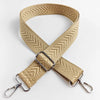 A beige woven strap with an arrow jacquard pattern is shown crossed and attached to a metal clip.