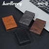 A collection of men's PU leather RFID blocking card holder wallets in brown, black, and dark gray placed on a laptop.